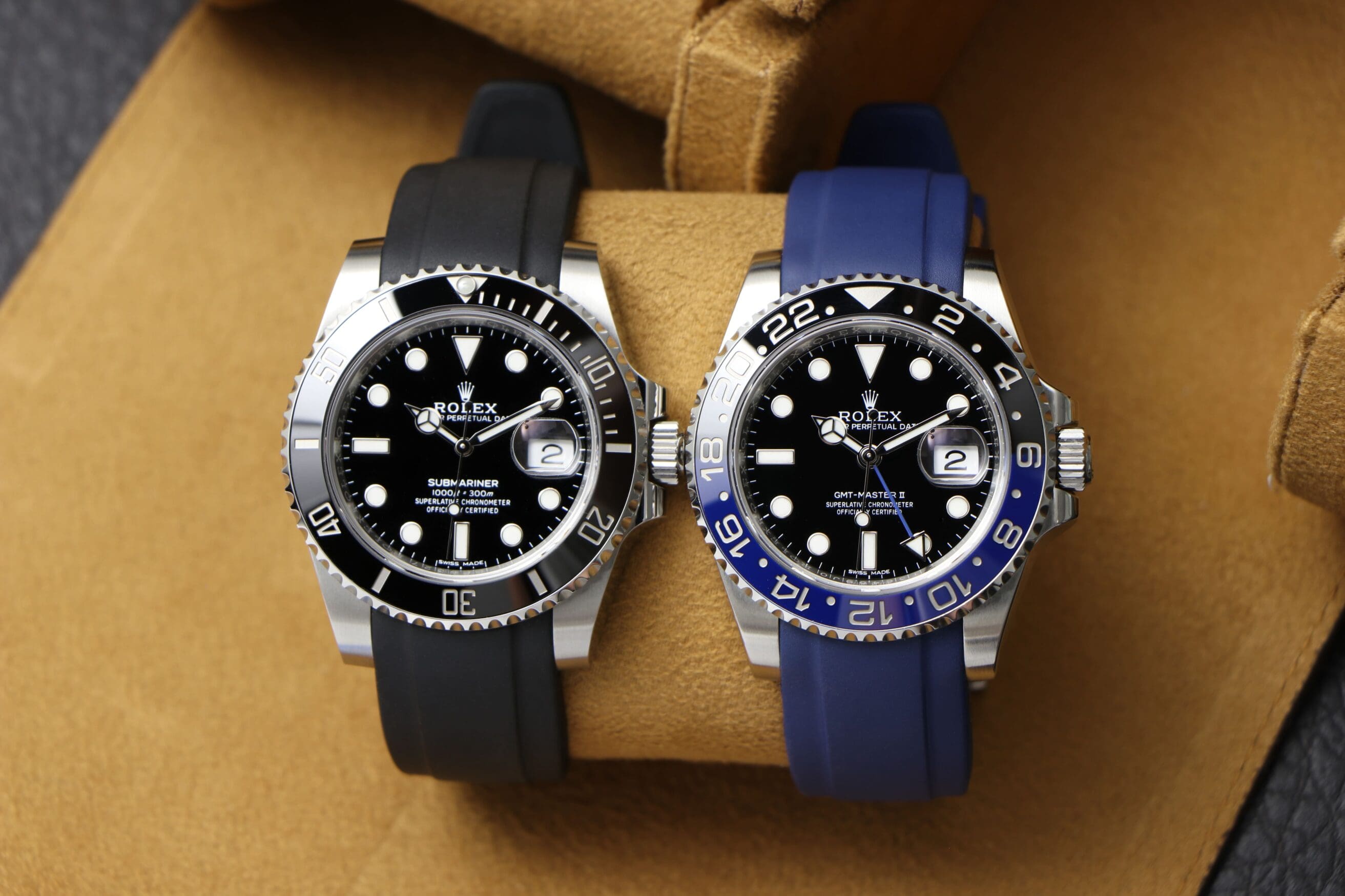 Two Rolex Submariner watches with a black and blue Everest rubber strap, respectively.