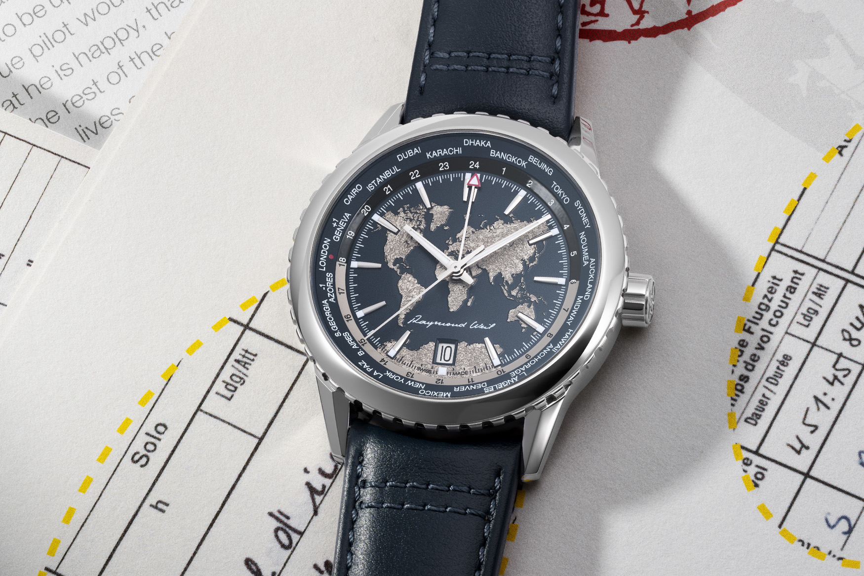 Raymond Weil Freelancer World-Traveller with silver world map dial and navy strap photographed on travel papers